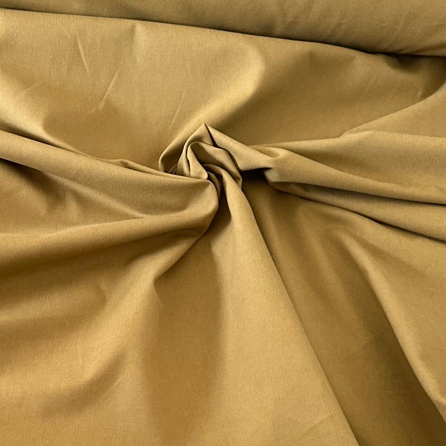 Gabardine 100 % coton kaki clair vendue au mètre. Tissu dense et résistant (240 g/m²), idéal pour pantalons, vestes et projets couture.