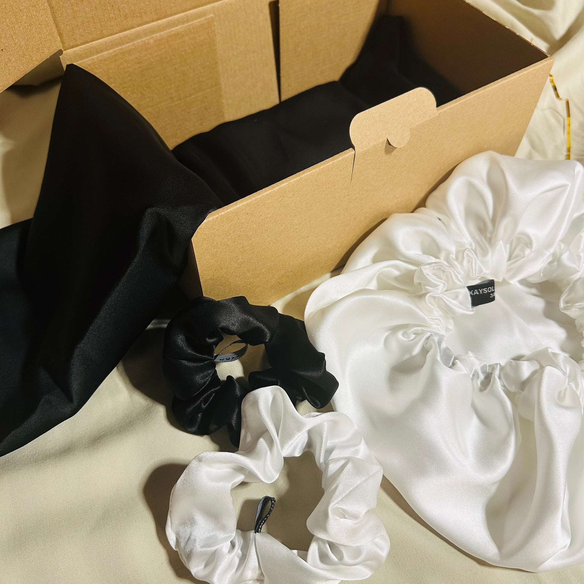 Coffret soie de mûrier noir et blanc cassé avec taie 22 mommes, bonnet réversible 19 mommes en soie des deux faces et chouchous assortis.