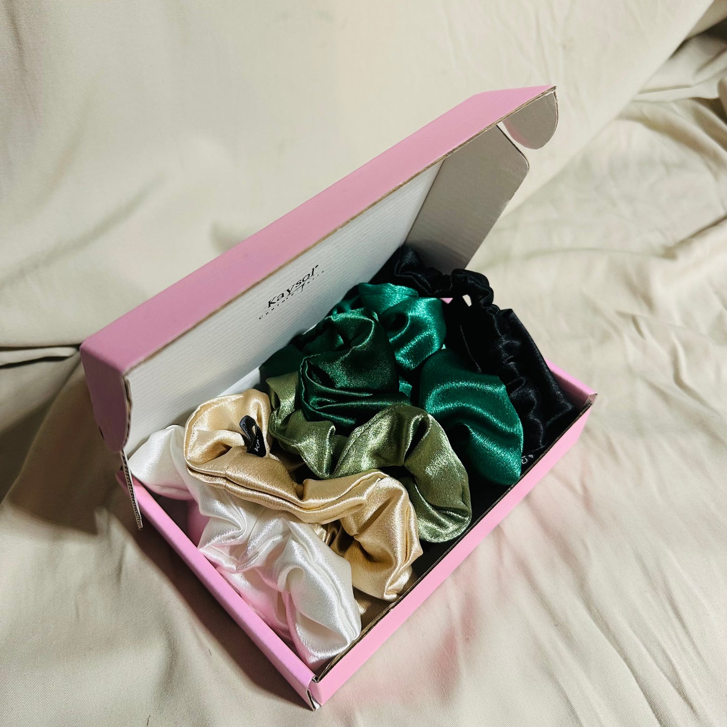 Coffret de 6 chouchous en satin premium, nuances vert et doré. Protège les cheveux, limite la casse et sublime vos coiffures. Livraison internationale.