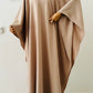 Robe longue Malia en crêpe lin de haute qualité, coupe fluide avec manches longues style cape, portée par mannequin femme. Taille unique ajustable grâce à des liens intérieurs. Couleur : beige / bleu marine / marron.