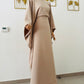 Robe longue Malia en crêpe lin beige, manches longues style cape, taille unique ajustable grâce à des liens intérieurs. Matière fluide et élégante, longueur au sol.