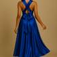 Trois mannequins présentent la robe Infinity satin bleu roi en trois longueurs différentes (genou, mi-mollet, longue) sur fond beige. Chaque robe est nouée dans un style distinct, mettant en valeur la brillance du satin et la coupe plissée fluide.
