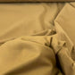 Gabardine 100 % coton kaki clair vendue au mètre. Tissu dense et résistant (240 g/m²), idéal pour pantalons, vestes et projets couture.